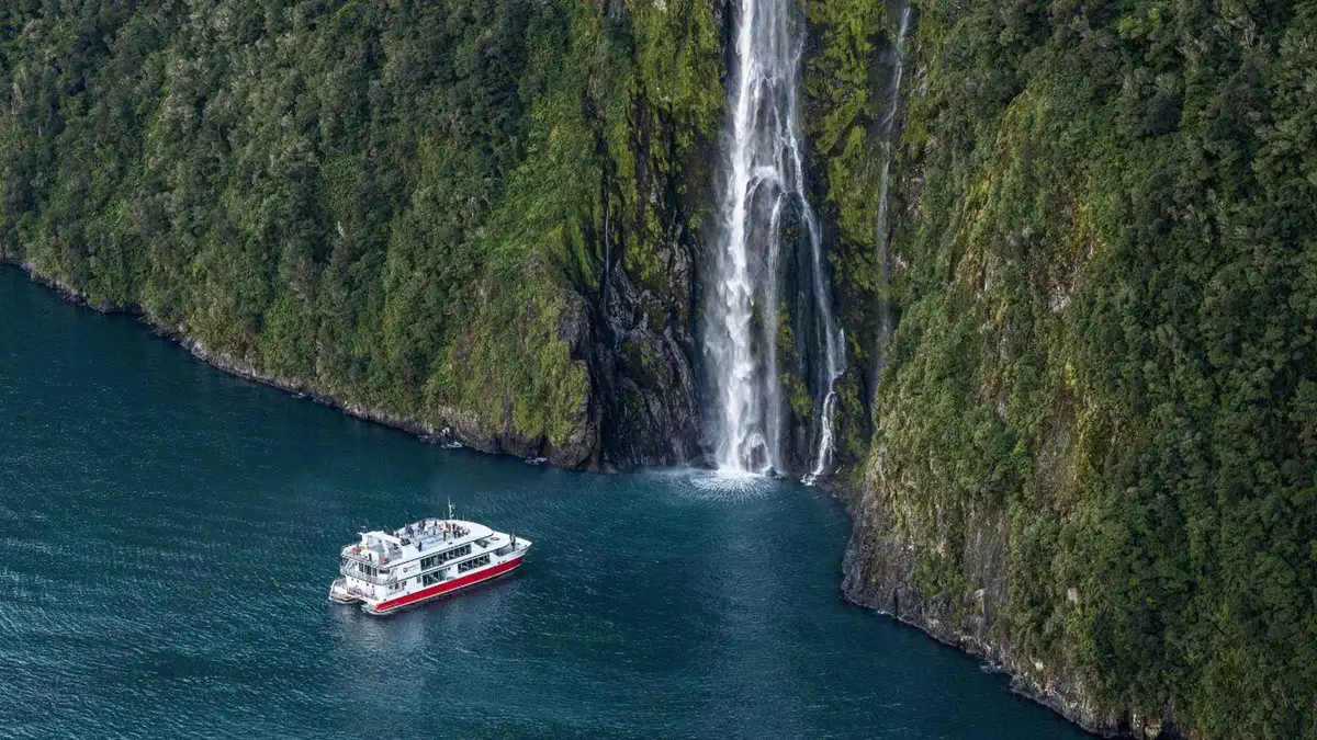 Catamaran cruising past Stirling Falls on a Milford Sound nature cruise in Fiordland, New Zealand