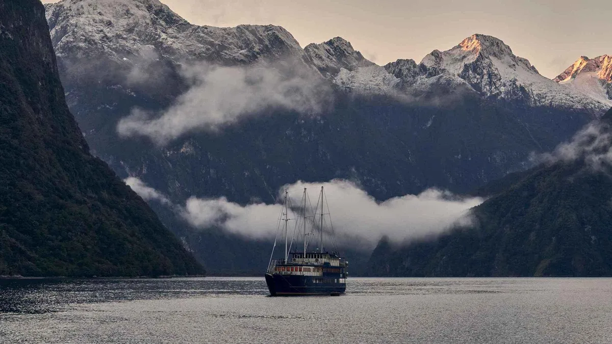 Overnight cruise vessel anchored in a sheltered cove on a Milford Sound overnight boat tour in Fiordland, New Zealand
