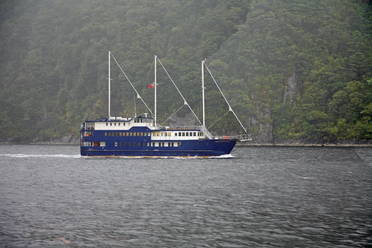 A cruise boat on Doubtful Sound beneath forested slopes on a Doubtful Sound cruise.