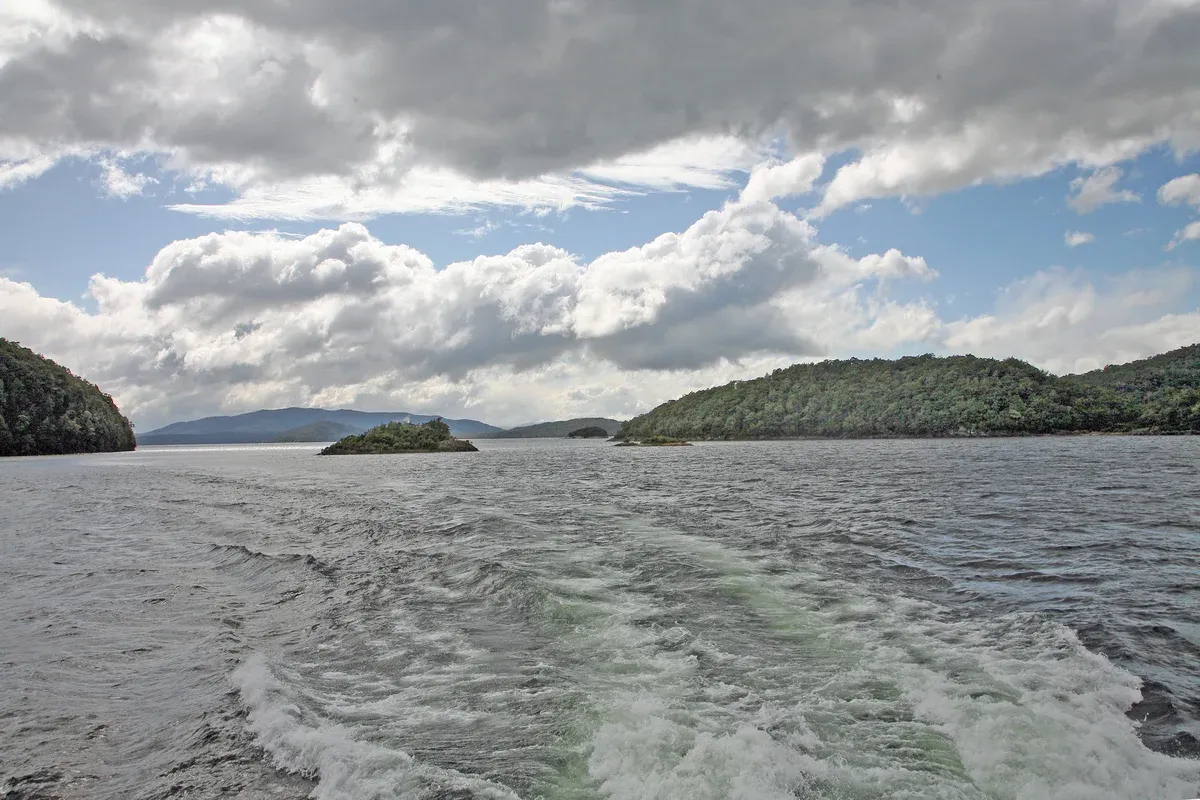 Lake Manapouri and its wooded islands under broken cloud on the way to a Doubtful Sound cruise.