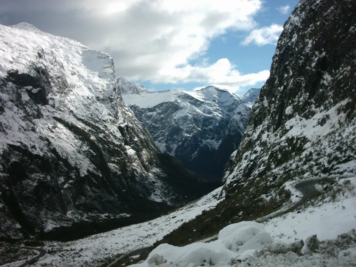 Snow and dark wet rock looking west from the Homer Tunnel portal into the Cleddau Valley on the road to a Milford Sound cruise