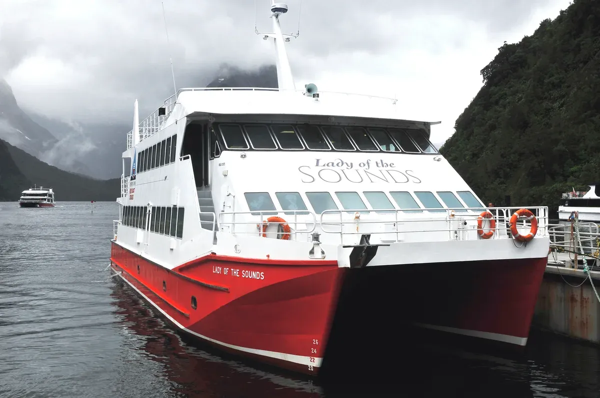 Red and white catamaran moored at the wharf, a typical Milford Sound cruise vessel