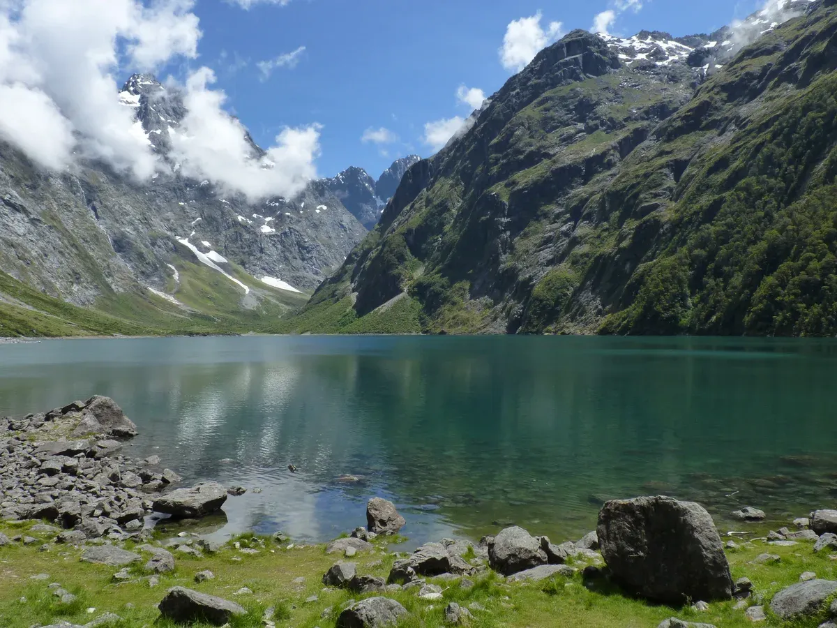 Lake Marian under rocky peaks, a walk off the Milford Road near a Milford Sound cruise