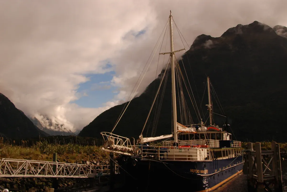 Milford Wanderer sailing-style boat docked on Milford Sound at dusk, a Milford Sound cruise vessel